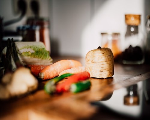 A variety of fresh vegetables on a wooden cutting board in a kitchen